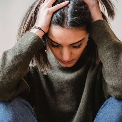 Una ragazza triste dopo aver ricevuto un feedback negativo; ha le mani sulla testa e i gomiti sulle ginocchia