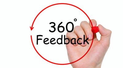 L'immagine mostra una mano con un pennarello. Il pennarello ha disegnato un cerchio con al centro la scritta Feedback 360 gradi