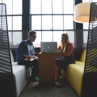 Due persone parlano del feedback 360 gradi in uno spazio riservato, con al centro un laptop