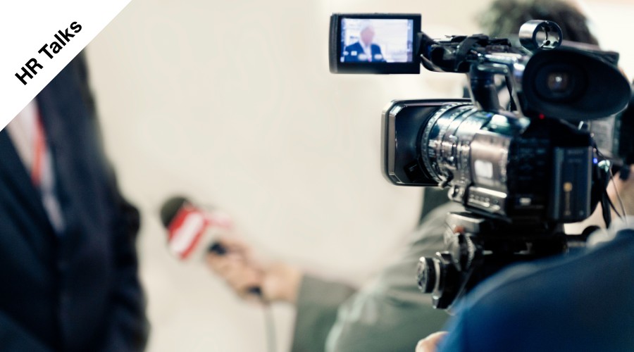 Un cameraman intervista la referente di Flamma Group, sullo sfondo