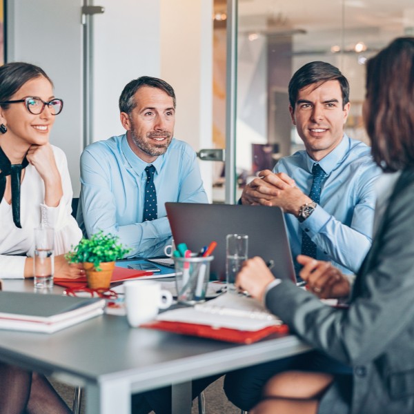 Il coaching manageriale: quattro manager riuniti al tavolo a parlare tra di loro