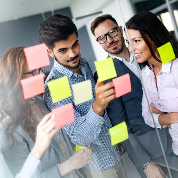 Attività di job crafting: 4 persone sono davanti a un vetro con attaccati dei post it